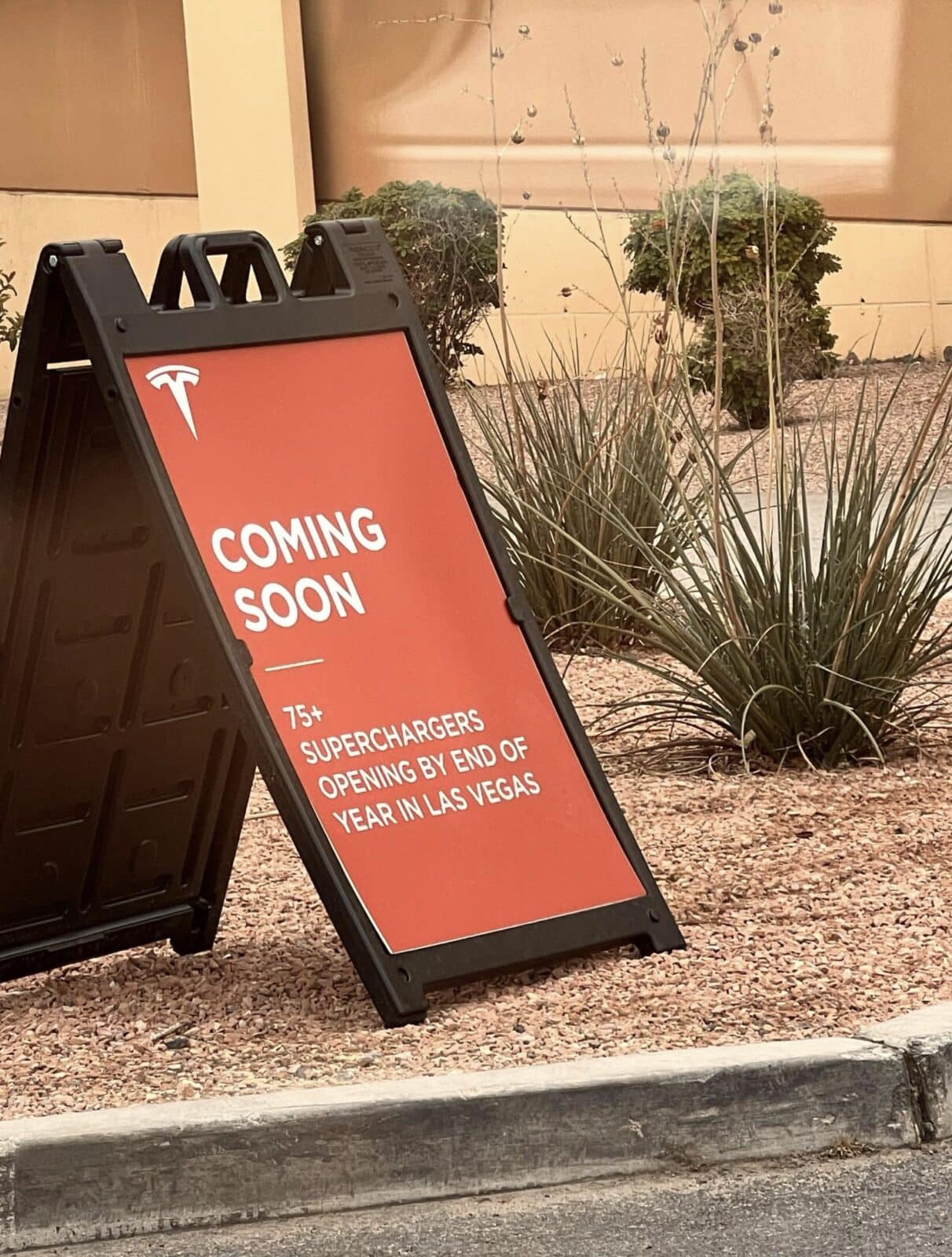 Tesla curb sign announcing more superchargers.