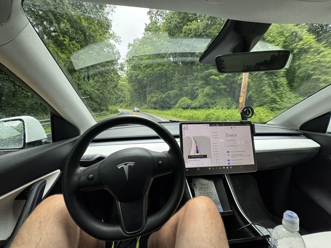 Driver's view from inside a Tesla, hands off the wheel with Autopilot navigation on the center display