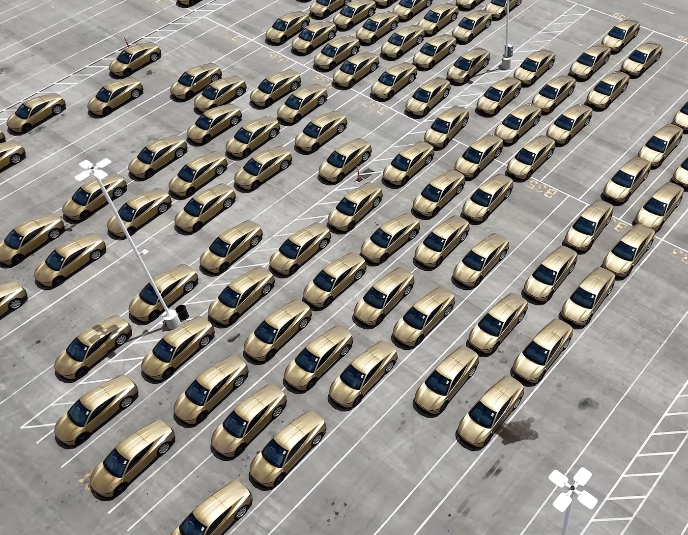 Rows of gold Tesla Cybercab vehicles staged in a parking lot at Gigafactory Texas