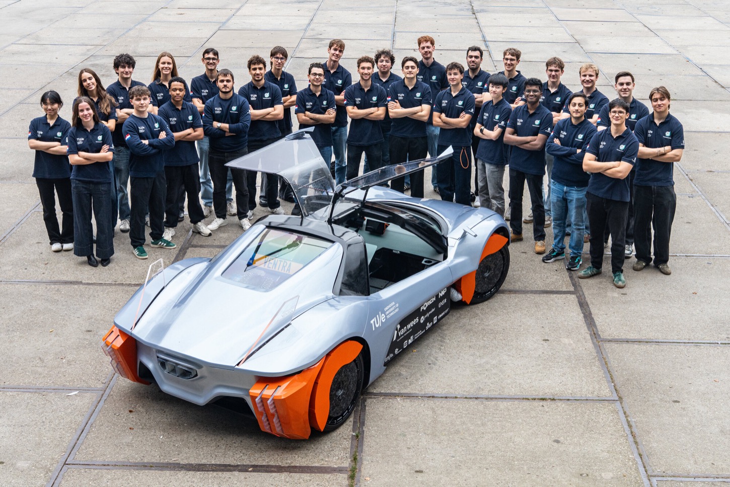 The TU/ecomotive student team standing behind the VENTRA concept car with its doors open