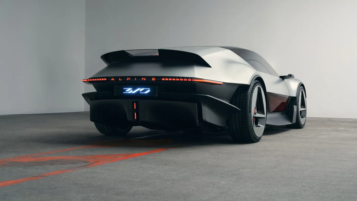 Rear three-quarter view of the Alpine A310 VISION showing the two-part rear wing, the thin red taillight bar with ALPINE lettering and an illuminated 310 badge