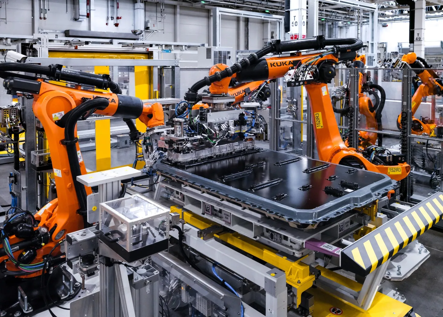 Orange KUKA robots lowering an Energy Master control unit onto a Gen6 battery pack on the Shenyang assembly line
