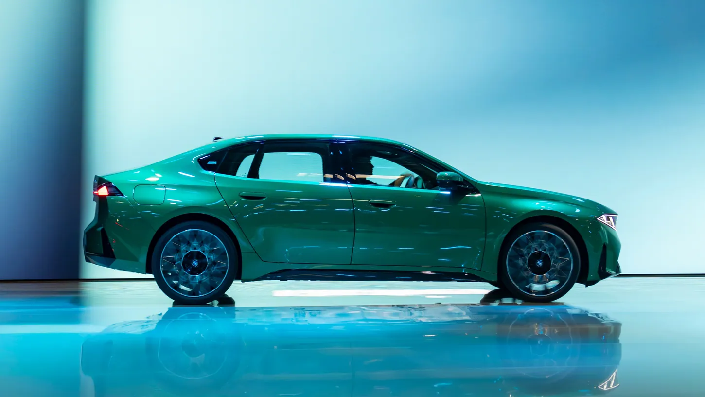 Green BMW i3 Long Wheelbase sedan in side profile on a reflective show stage