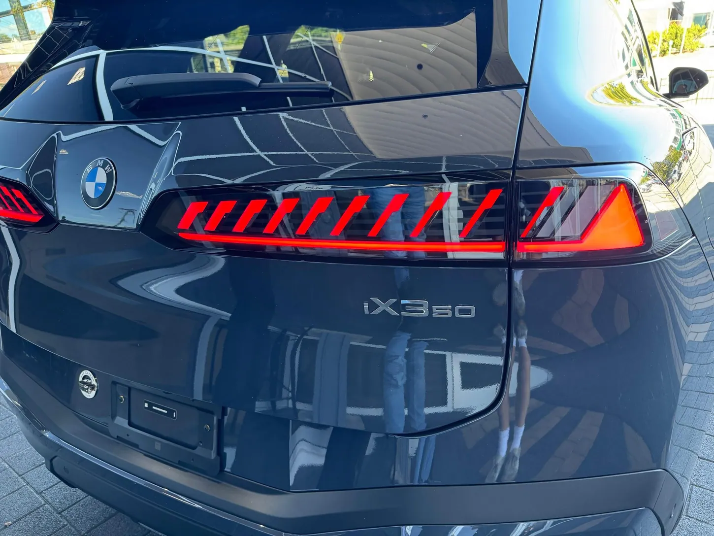Close-up of a dark BMW iX3 tailgate with red slatted LED taillights and the iX3 50 badge