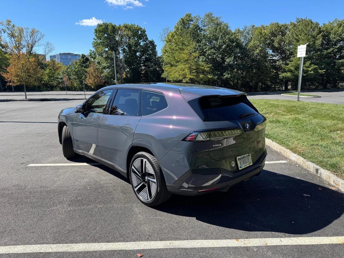 Gray BMW iX3 50 xDrive seen from the rear three-quarter angle in a parking lot