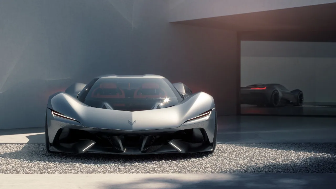 Silver Chevrolet Corvette CX concept seen head-on on a gravel courtyard, with a dark concept car parked in the background