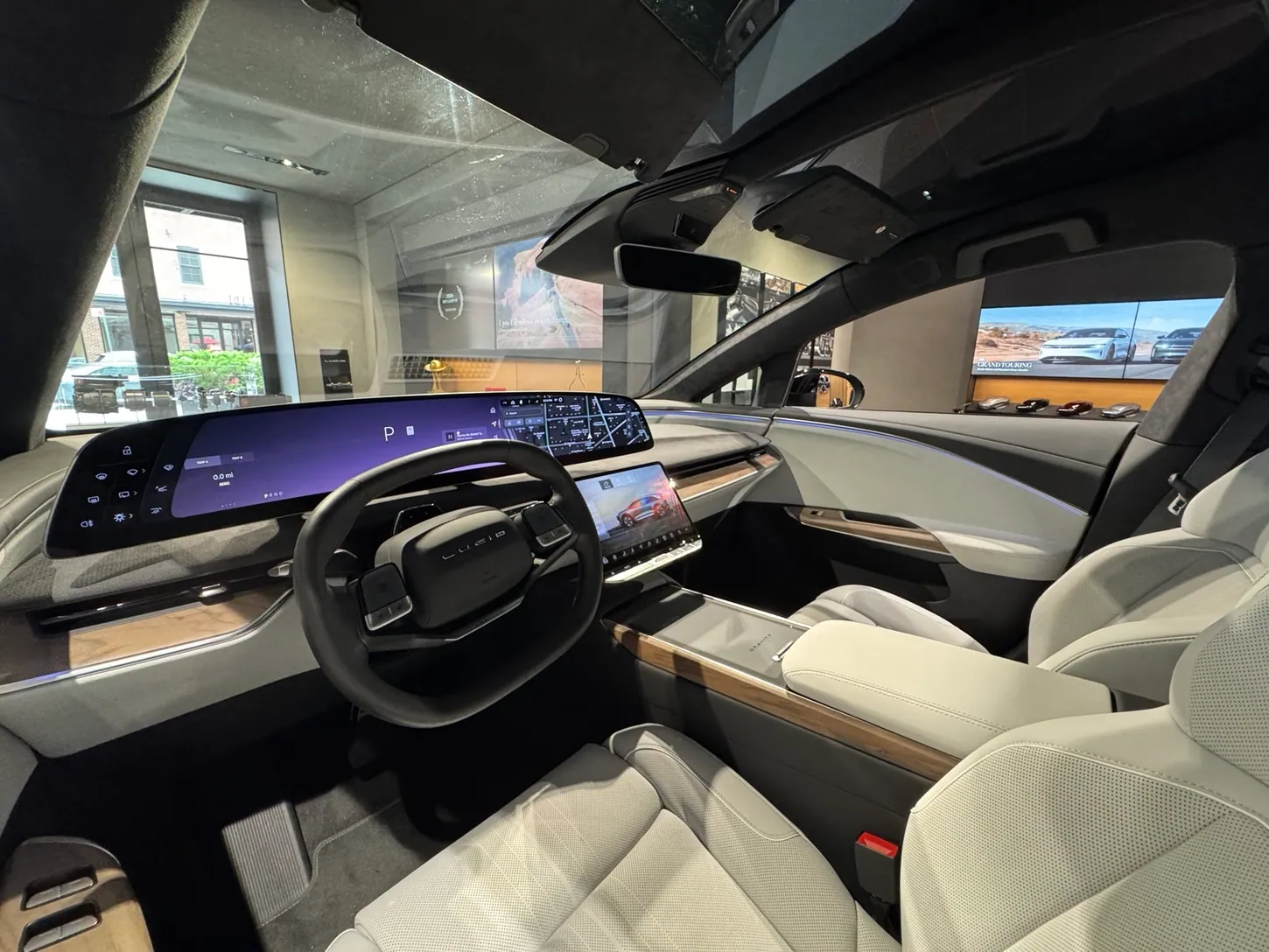 Driver's seat view of the Lucid Gravity interior with the curved display, steering wheel and light grey seats