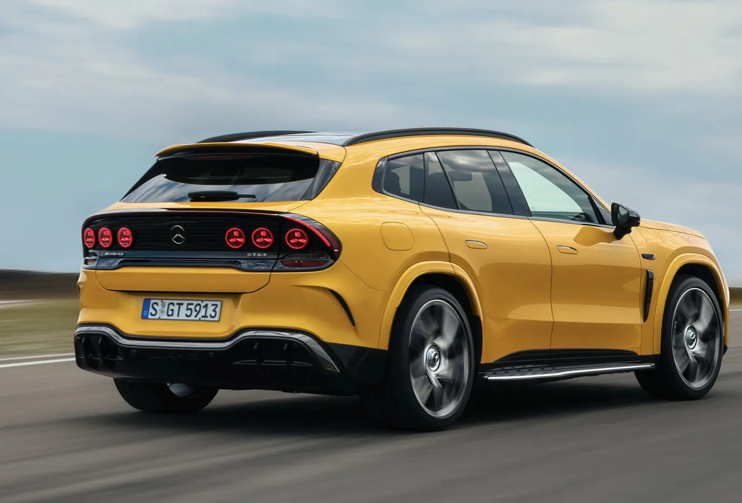Yellow Mercedes-AMG GT 63 SUV driving on a test track, seen from the rear with six round red taillights and a roof spoiler