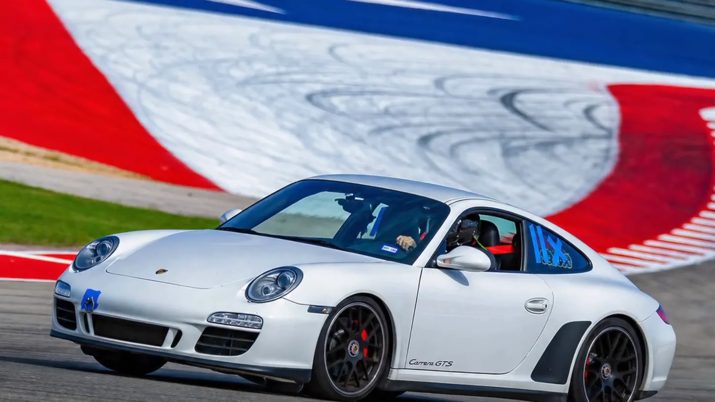 White Porsche 911 Carrera GTS cornering on the red, white and blue painted runoff at Circuit of the Americas