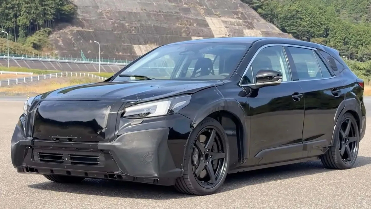 Black Subaru EV test car with a modified Outback body and riveted panels parked on a test track in Japan