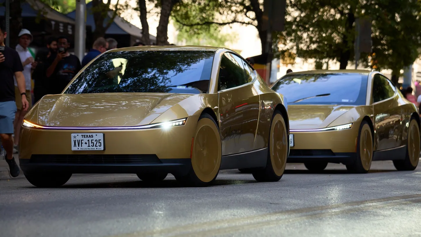 Two gold Tesla Cybercabs with Texas plates driving down a tree-lined Austin street as people film them from the sidewalk