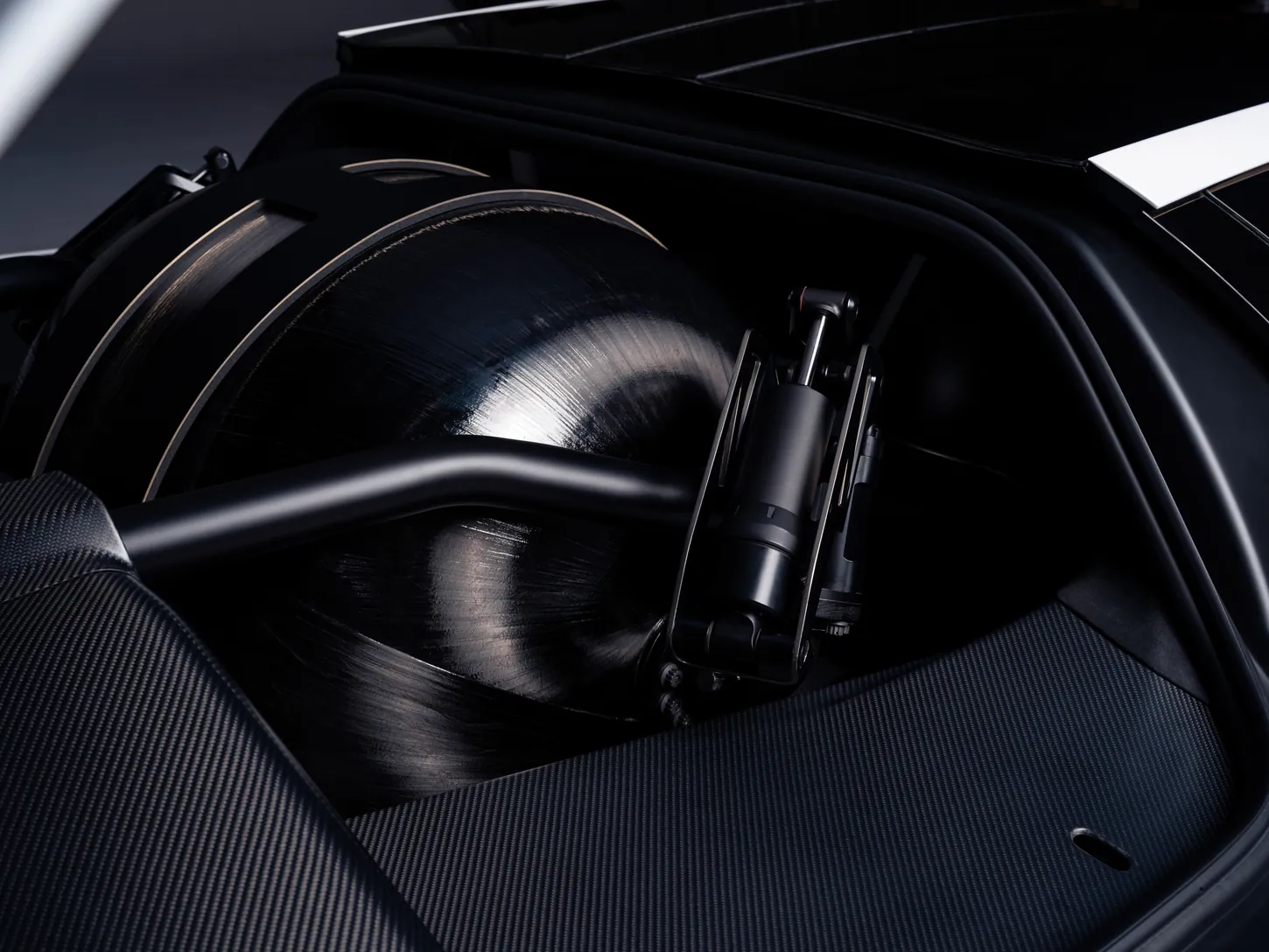 Dark carbon fiber wrapped spherical pressure tank tucked behind the Tesla Roadster cabin, next to a roll hoop and a suspension strut
