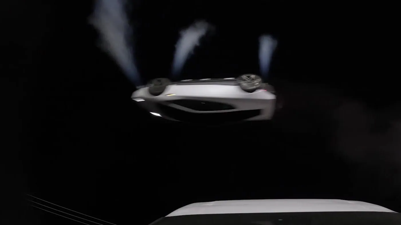 White Tesla Roadster upside down in midair at night with three thruster plumes streaming upward from its underside, the roof of a Tesla Semi below