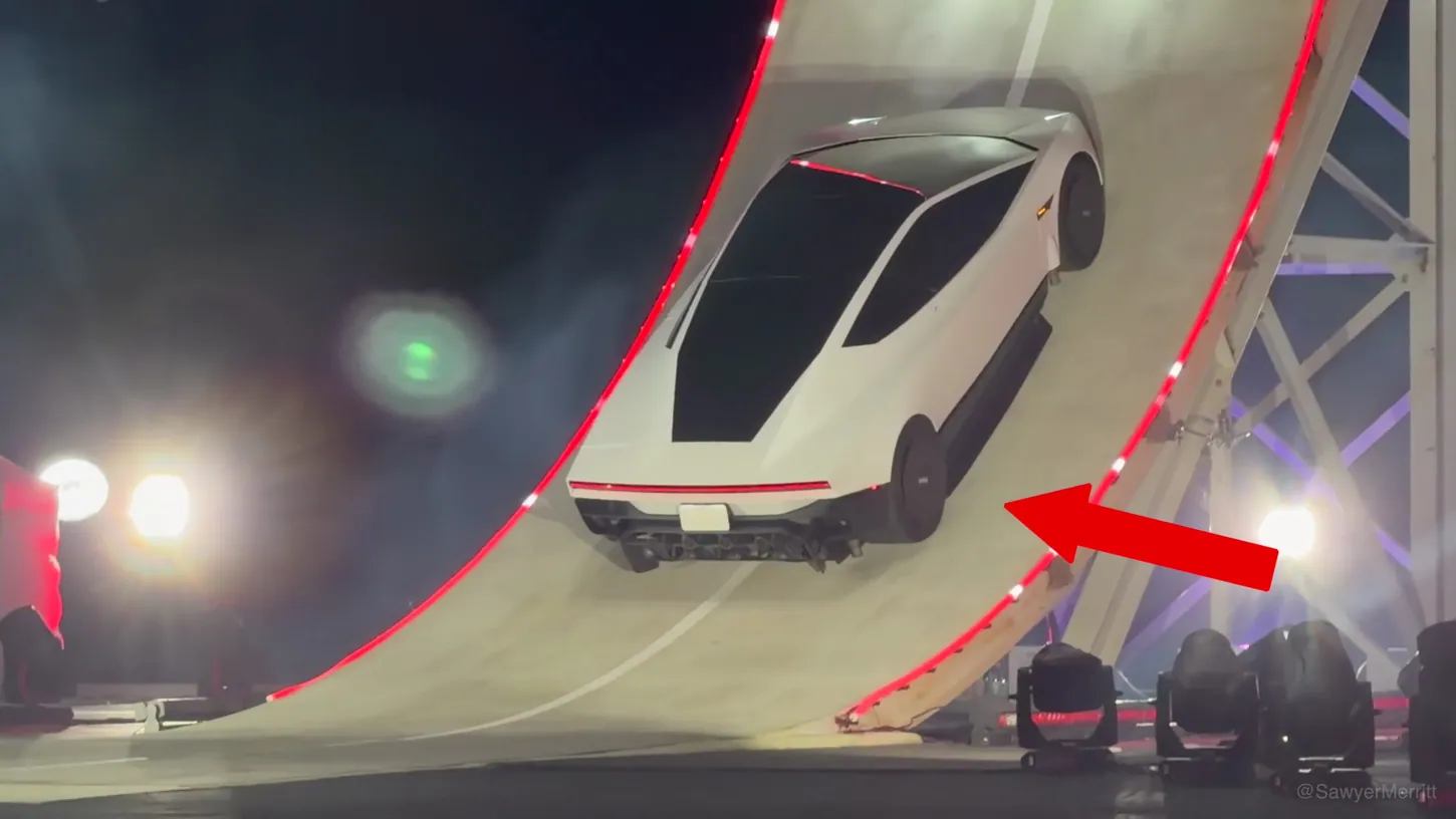 White Tesla Roadster driving on a near-vertical curved ramp at night, a red arrow pointing at the dark side skirt below its doors