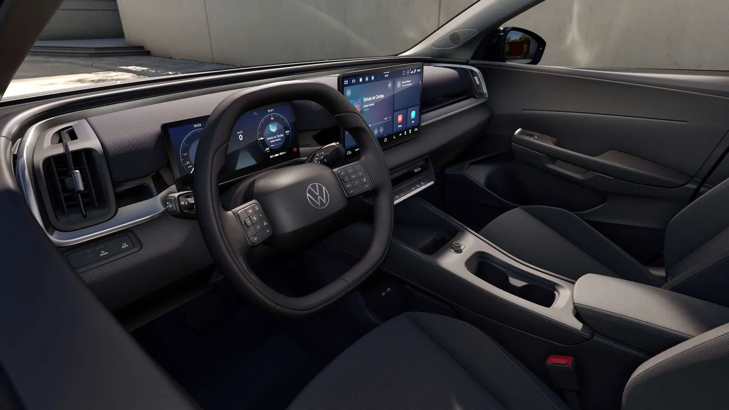 Volkswagen ID. Cross dashboard with a two-spoke steering wheel, a small driver display and a central touchscreen, seen from the driver's door