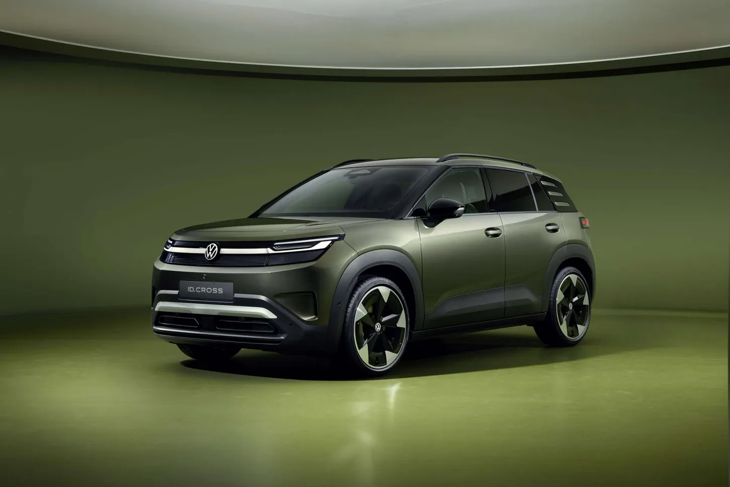 Dark green Volkswagen ID. Cross electric SUV with two-tone wheels in a curved green studio