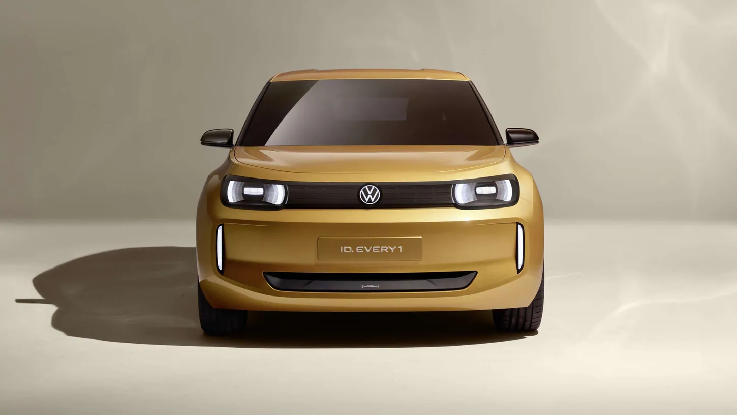 Yellow Volkswagen ID. EVERY1 concept hatchback seen head-on in a beige studio